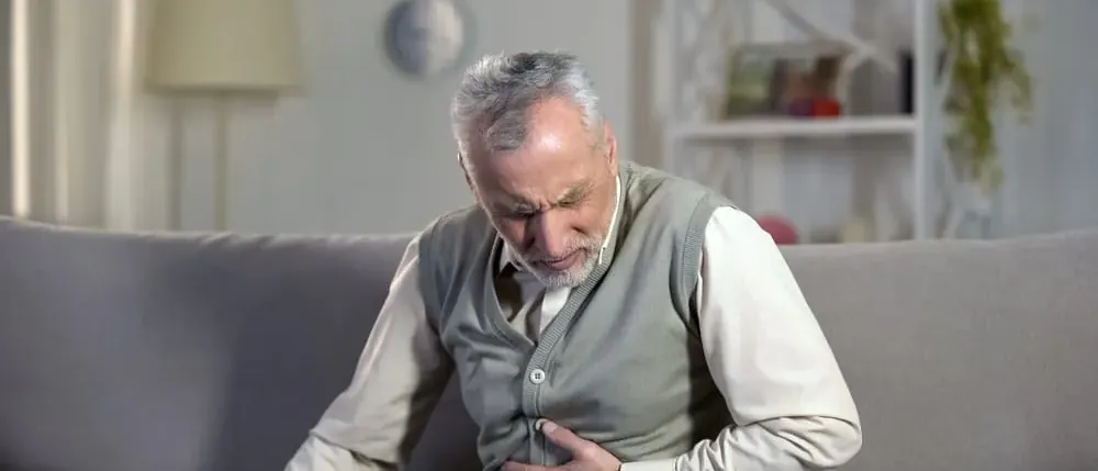 Man on a couch with abdominal pain, a possible sign of Covidien hernia mesh complications