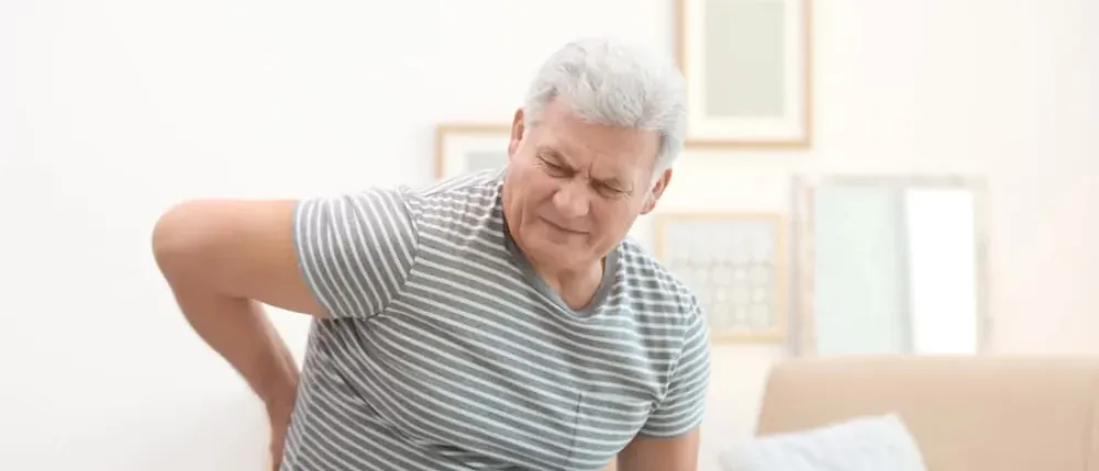 Older man holding his side in pain from hernia mesh complications