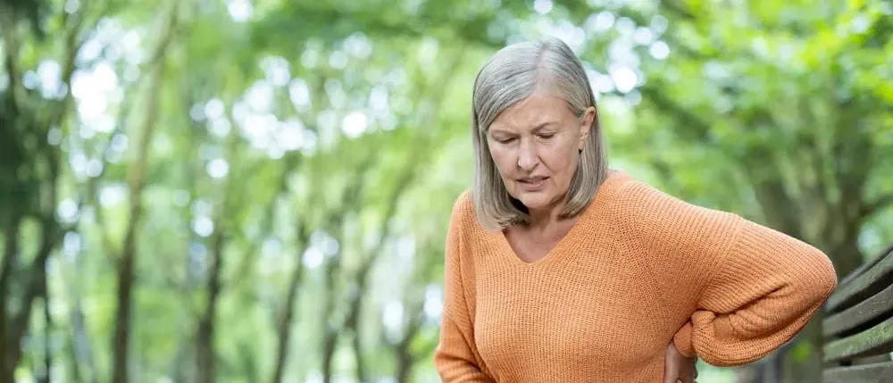 Woman on a park bench in pain from Covidien Parietex hernia mesh complications